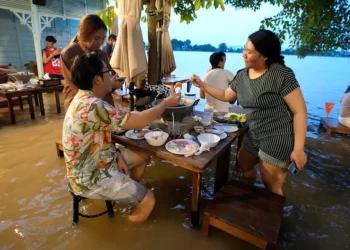 Flooded Thai restaurant becomes a hit with local diners, who dodge waves from passing boats while eating their meals